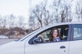Young woman driving a car in the city. Portrait of a beautiful woman in a car, looking out of the window and smiling. Travel and Royalty Free Stock Photo