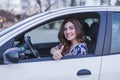 Young woman driving a car in the city. Portrait of a beautiful woman in a car, looking out of the window and smiling. Travel and Royalty Free Stock Photo