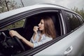 Young woman driving a car. The girl paints her lips in the car. Woman doing makeup in the car. Royalty Free Stock Photo