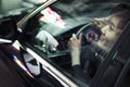 Young woman driving and looking through car window at the city night lights Royalty Free Stock Photo