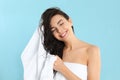 Young woman drying hair with towel on blue background