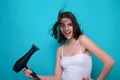 Young woman drying her hair with a hairdryer isolated on studio background. Young woman with blow dryer drying hair Royalty Free Stock Photo