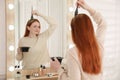 Young woman dyeing hair with henna near mirror