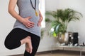 Young woman in early pregnancy doing tree pose holding belly