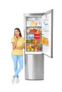 Young woman eating apple near open refrigerator