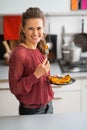 Young woman eating baked pumpkin in kitchen