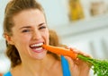 Young woman eating carrot in kitchen Royalty Free Stock Photo
