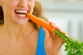 Young woman eating carrot in kitchen Royalty Free Stock Photo