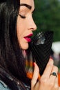 Young woman eating dark black cone ice-cream. Close-up portrait female with red lips.