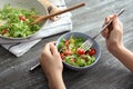 Young woman eating delicious quinoa salad at wooden table