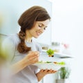 Young woman eating fresh salad in modern kitchen Royalty Free Stock Photo