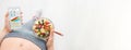 Young woman is eating a fruit salad and using a fitness app on her smartphone. Royalty Free Stock Photo