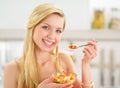 Young woman eating fruits salad in kitchen Royalty Free Stock Photo