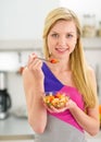 Young woman eating fruits salad in kitchen Royalty Free Stock Photo