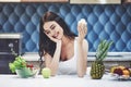 Young woman eating healthy salad with cherry tomatoes in the kitchen after a fitness session Royalty Free Stock Photo