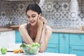 Young woman eating healthy salad with cherry tomatoes in the kitchen after a fitness session Royalty Free Stock Photo