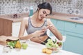 Young woman eating healthy salad with cherry tomatoes in the kitchen after a fitness session Royalty Free Stock Photo