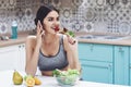 Young woman eating healthy salad with cherry tomatoes in the kitchen after a fitness session Royalty Free Stock Photo