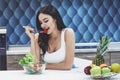 Young woman eating healthy salad with cherry tomatoes in the kitchen after a fitness session Royalty Free Stock Photo