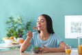 Young woman eating healthy salad with vegetables in kitchen Royalty Free Stock Photo