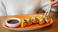 Young woman eating japanese gedza dumplings in cafe