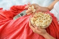 Young woman eating popcorn while watching TV in bedroom, closeup Royalty Free Stock Photo