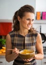 Young woman eating pumpkin soup in kitchen Royalty Free Stock Photo