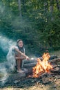 Young woman eating roasted marshmallows while camping near the lake. Woman roasting marshmallows near bonfire. Young