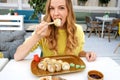 Young woman eating rolls in cafe. Close-up portrait.