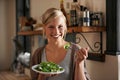 Young, woman and eating a salad in kitchen with a smile with wellness and lettuce for cooking. Girl, healthy and Royalty Free Stock Photo