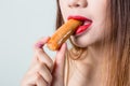 Young woman eating sausage or hotdog. girl is sitting in the kitchen and greedily eats sausage. Royalty Free Stock Photo