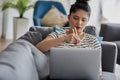 Young woman eating something with sticks in front of laptop Royalty Free Stock Photo