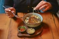 Young woman eating soup served in a white bowl. Eating out. Restaurant concept. Woman` s hand holding spoon. Royalty Free Stock Photo