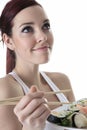 Young woman eating a sushi piece against a white