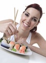 Young woman eating a sushi piece against a white