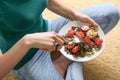 Young woman eating tasty chicken salad with vegetables while sitting on floor Royalty Free Stock Photo