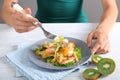 Young woman eating tasty chicken salad with vegetables at table Royalty Free Stock Photo