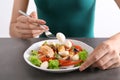 Young woman eating tasty chicken salad with vegetables at table Royalty Free Stock Photo