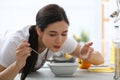 Young woman eating tasty vegetable soup at countertop