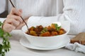 Young woman is eating traditional homemade Hungarian beef meat stew and soup - Goulash Royalty Free Stock Photo