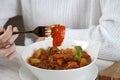 Young woman is eating traditional homemade Hungarian beef meat stew and soup - Goulash Royalty Free Stock Photo