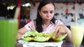 A young woman is eating a very hot Indian dish in a tropical cafe.