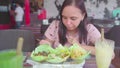 A young woman is eating a very hot Indian dish in a tropical cafe.