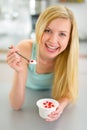 Young woman eating yogurt in kitchen Royalty Free Stock Photo