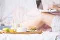 Young woman eats a healthy breakfast in bed with a laptop Royalty Free Stock Photo