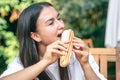 A young woman eats a hot dog on a cafe terrace. Royalty Free Stock Photo