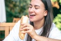A young woman eats a hot dog on a cafe terrace. Royalty Free Stock Photo
