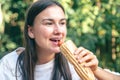 A young woman eats a hot dog on a cafe terrace. Royalty Free Stock Photo