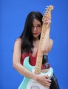 Woman with long black hair poses with light blue electric guitar Royalty Free Stock Photo
