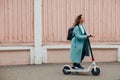 Young woman with electric scooter in blue coat at the city Royalty Free Stock Photo